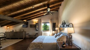 A bedroom with a wooden ceiling, a bed with a white bedspread, a nightstand with a lamp, and a view of the outdoors through a window. - La Casona de Valfrío (Cuacos de Yuste)