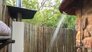 A wooden fence with a water feature, a stone wall, and a metal structure.