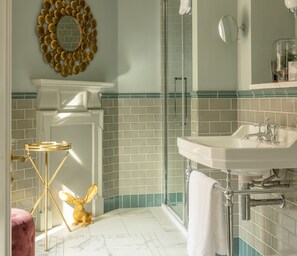 A bathroom with a white sink, a mirror, a towel rack, and a shower area. - The Wilder (Dublin)