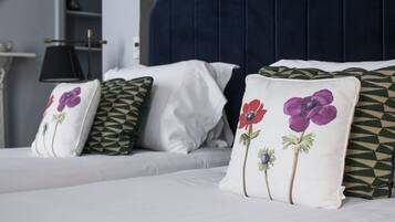 A bed with white bedding and decorative pillows featuring floral designs.