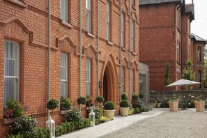 A brick building with a courtyard, potted plants, and outdoor seating. - The Wilder (Dublin)