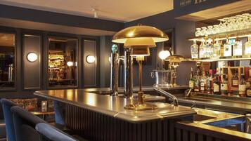 A bar area with a counter, stools, and a bar stocked with bottles.