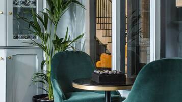 Een modern interieur met een groen bekleden stoel, een kleine ronde tafel en een potplant.