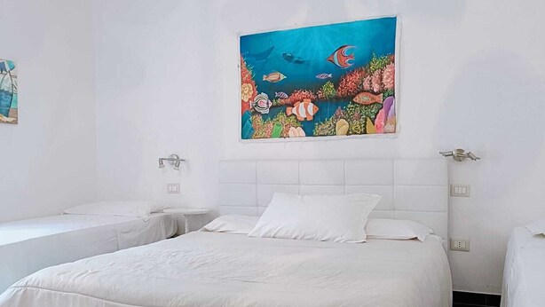 Habitación de hotel con una cama grande, dos mesitas de noche y un mural colorido que muestra una escena submarina.