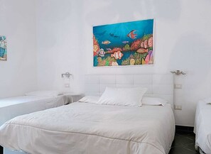 Une chambre d’hôtel avec un grand lit, deux tables de chevet et une fresque colorée représentant une scène sous-marine.