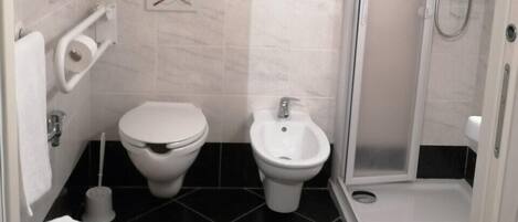 Une salle de bain moderne équipée de toilettes, d’un bidet et d’une douche à l’italienne.