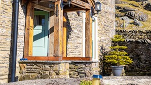 A stone building with a wooden porch, a door, and a window. - Middle Studfold Farm B&B (Settle)