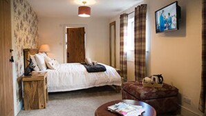 A bedroom with a bed, bedside table, lamp, and a television on the wall. - Middle Studfold Farm B&B (Settle)