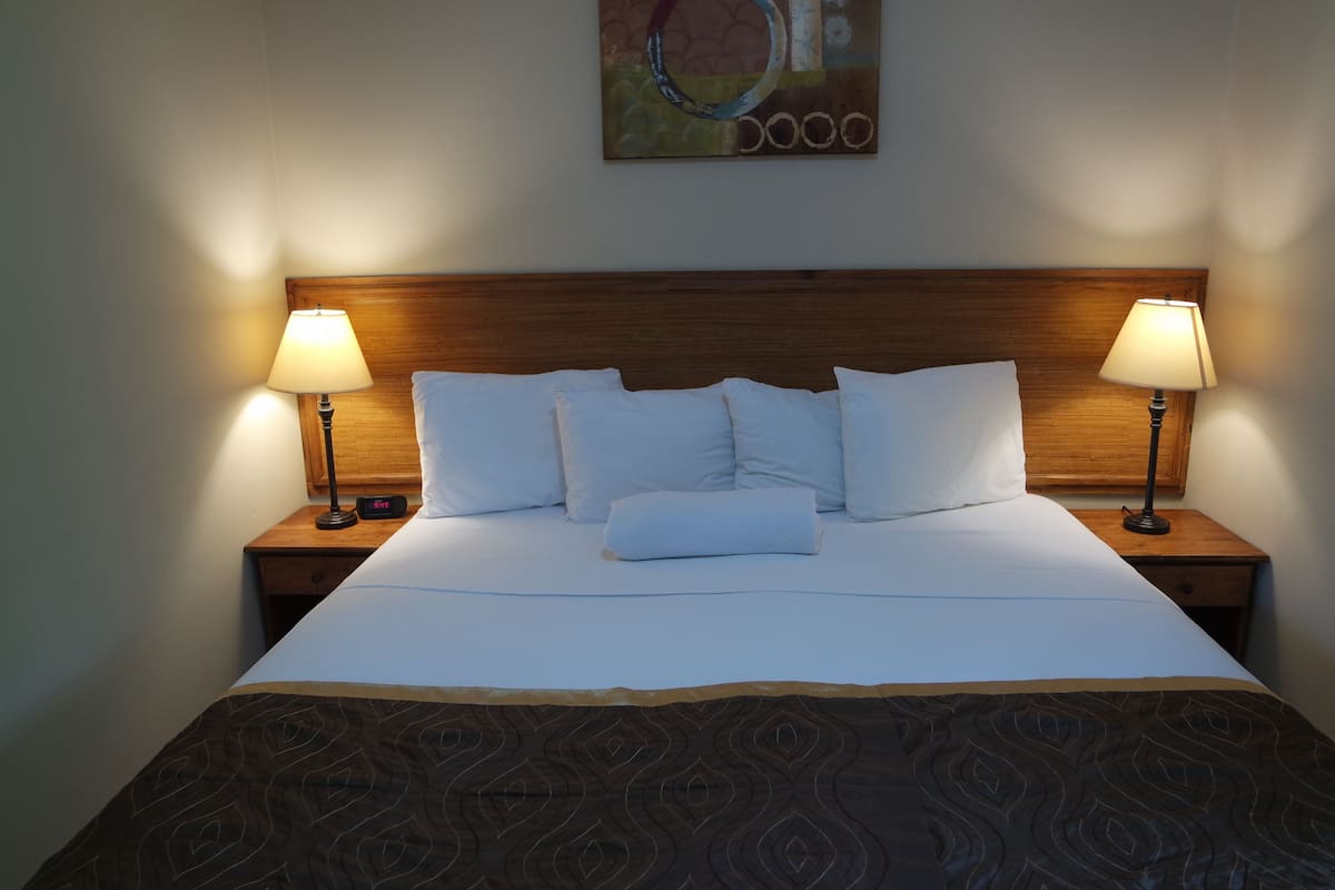 A neatly made bed with white linens and a patterned bedspread, flanked by two bedside lamps on wooden nightstands.
