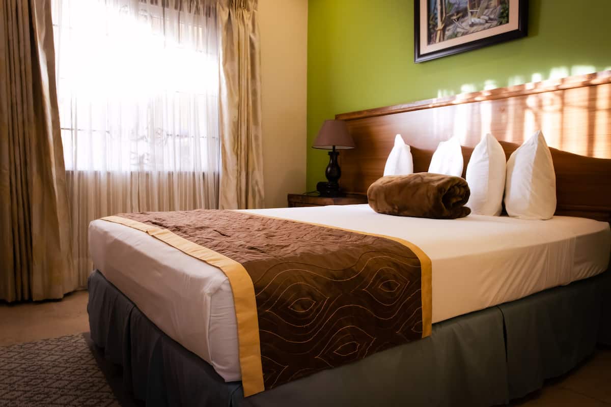 A neatly made bed with a patterned bedspread, a wooden headboard, and a pillow arrangement.