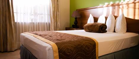 Una cama bien hecha con un edredón estampado, un cabecero de madera y un arreglo de almohadas.