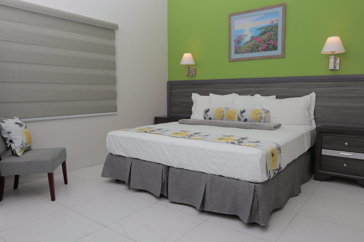 A neatly arranged bedroom with a bed, bedside tables, and a chair.