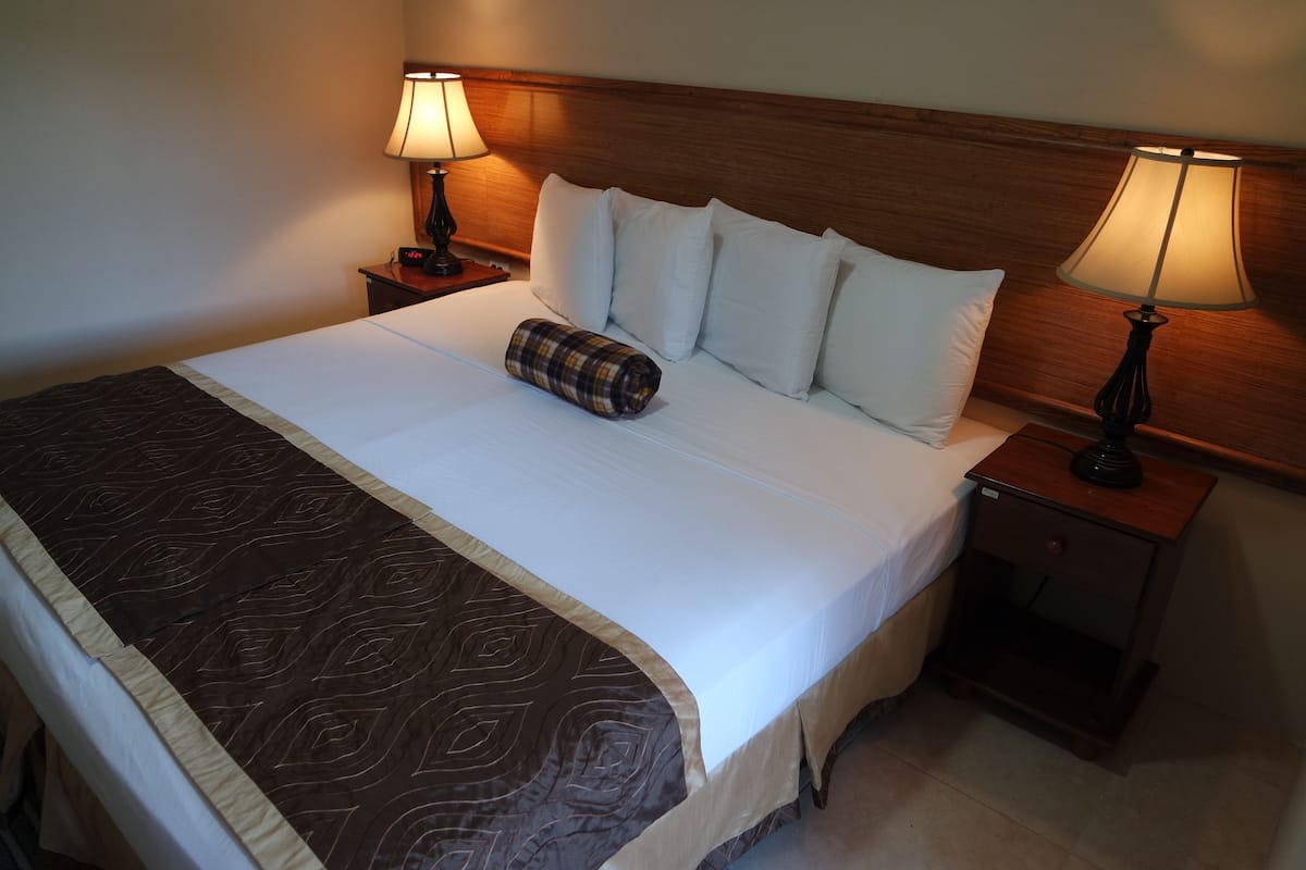 A neatly made bed with a patterned bedspread, two bedside lamps, and a wooden headboard.