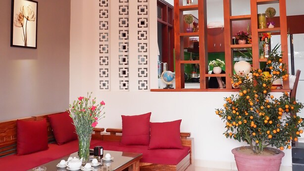 A modern living room with a wooden sofa, a glass-top coffee table, and a ceiling fan. - White Lion House (Da Nang)