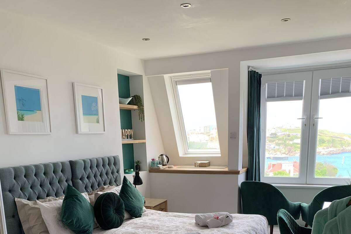 Un dormitorio con una cama grande, una ventana con vistas, un escritorio y una silla.