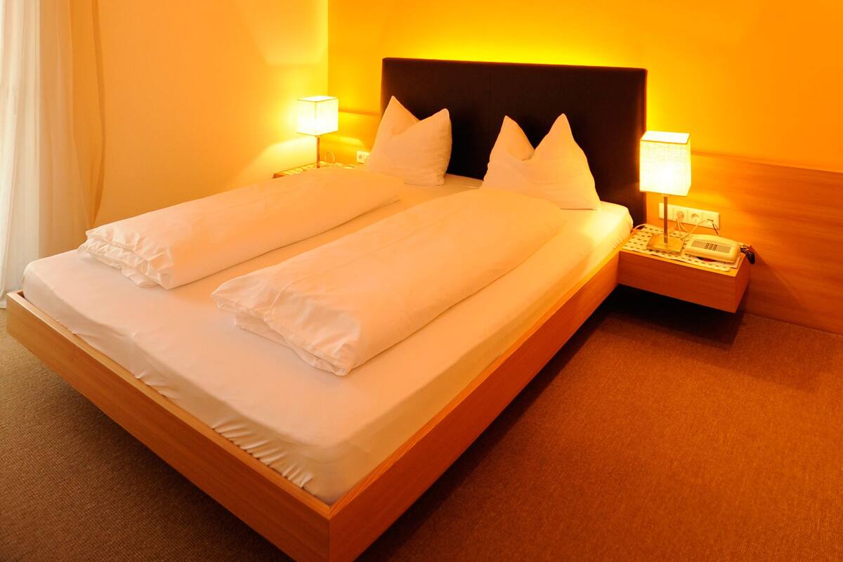 Ein Hotelzimmer mit einem großen Bett, zwei Nachttischen und einem Kopfteil.