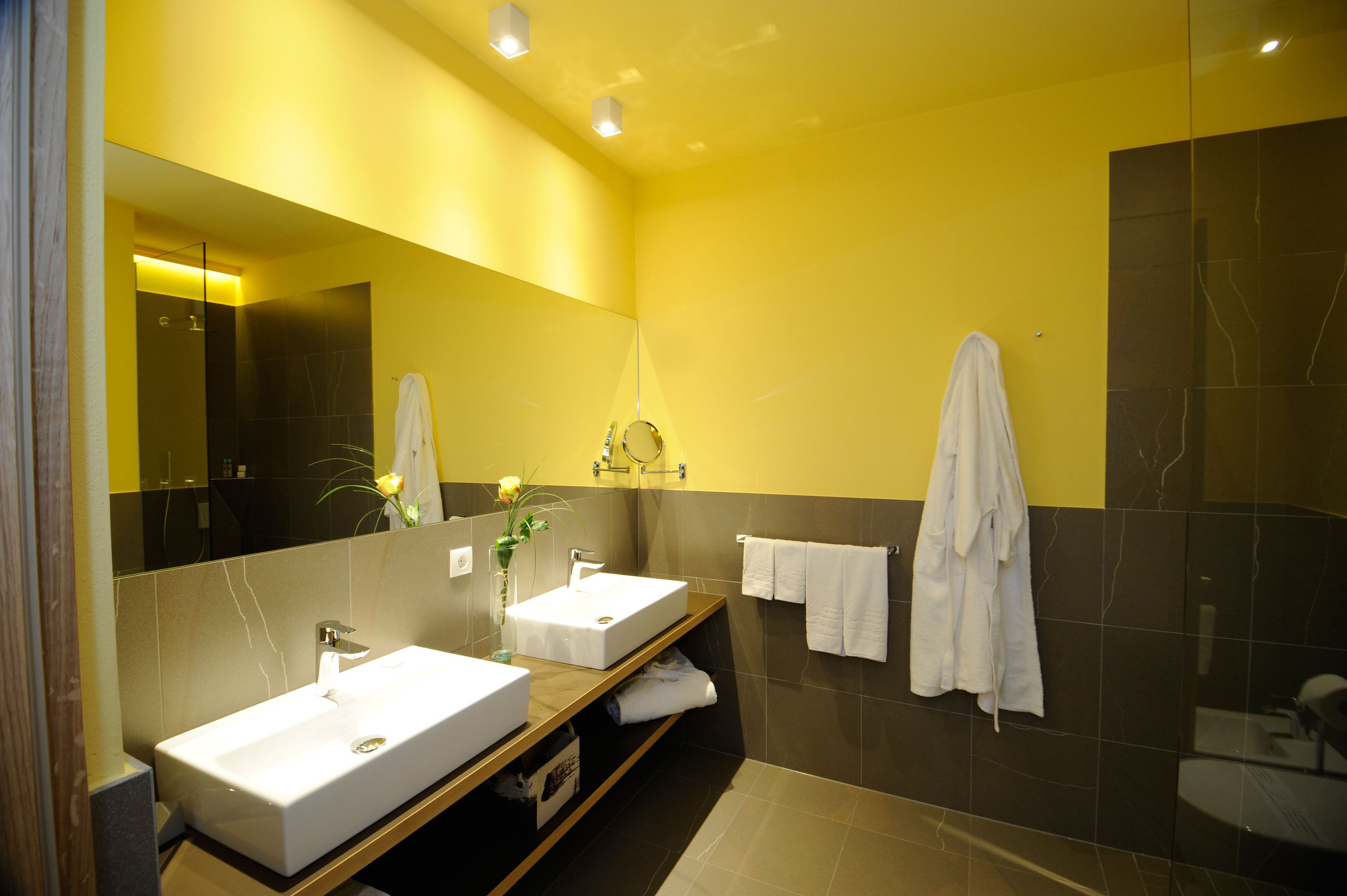 Un bagno moderno con due lavabi, un grande specchio e cabina doccia.
