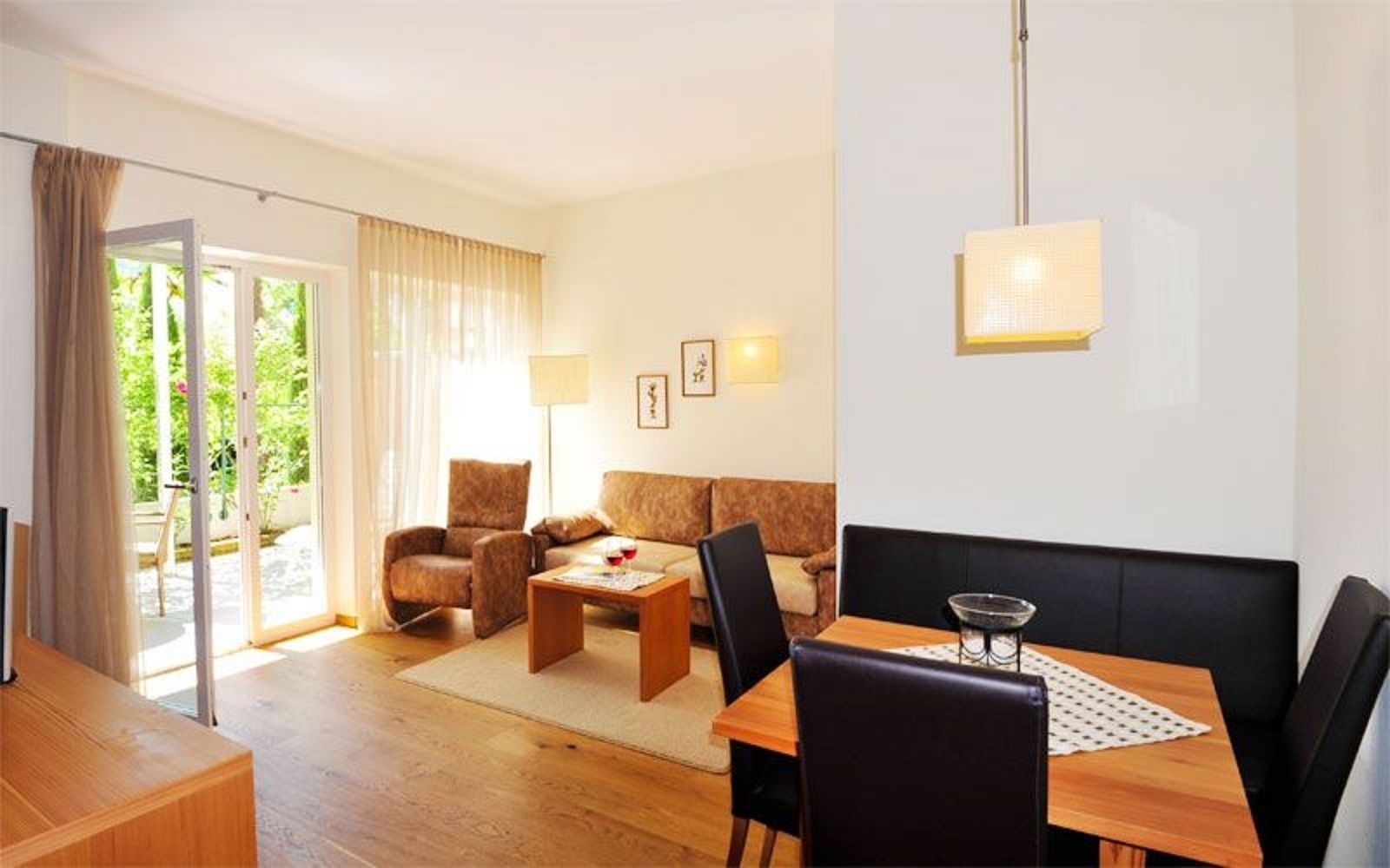 A modern living room with a sofa, armchair, coffee table, and dining table.