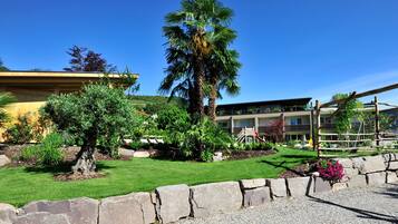 Ein Hotel mit gepflegtem Garten, einer Palme und einem Spielbereich.