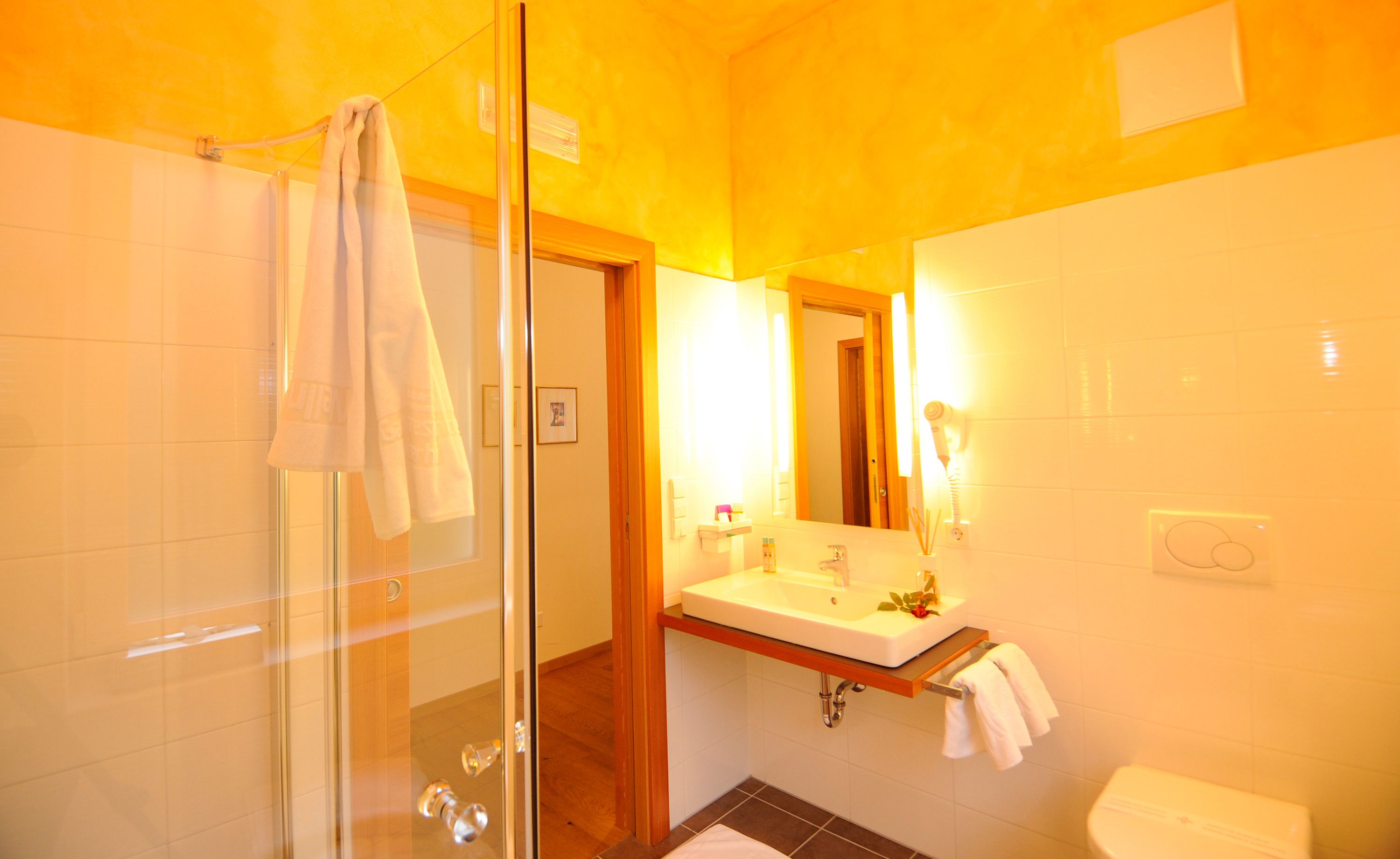 A bathroom with a glass shower enclosure, a sink with a mirror, and a toilet.