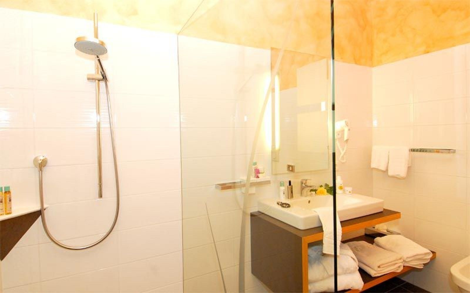 Un baño moderno con cabina de ducha de vidrio, tocador con espejo y inodoro.