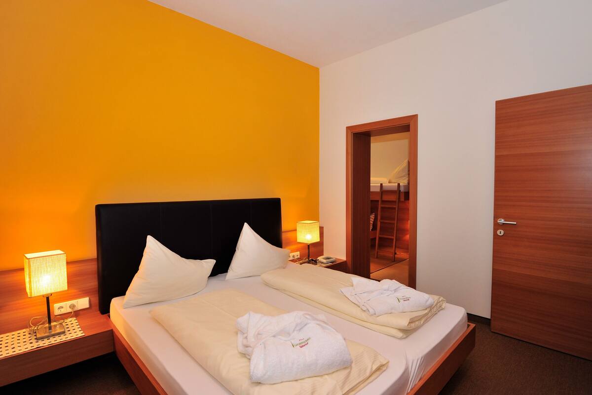 Ein Hotelzimmer mit einem Bett, zwei Nachttischen, einer Kommode, einer Holztür und einem Spiegel.