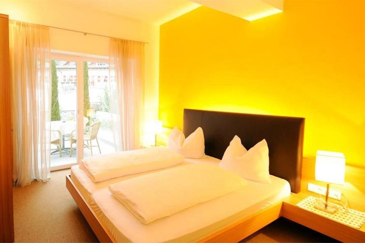 Ein Hotelzimmer mit Bett, Nachttisch und Blick nach außen.