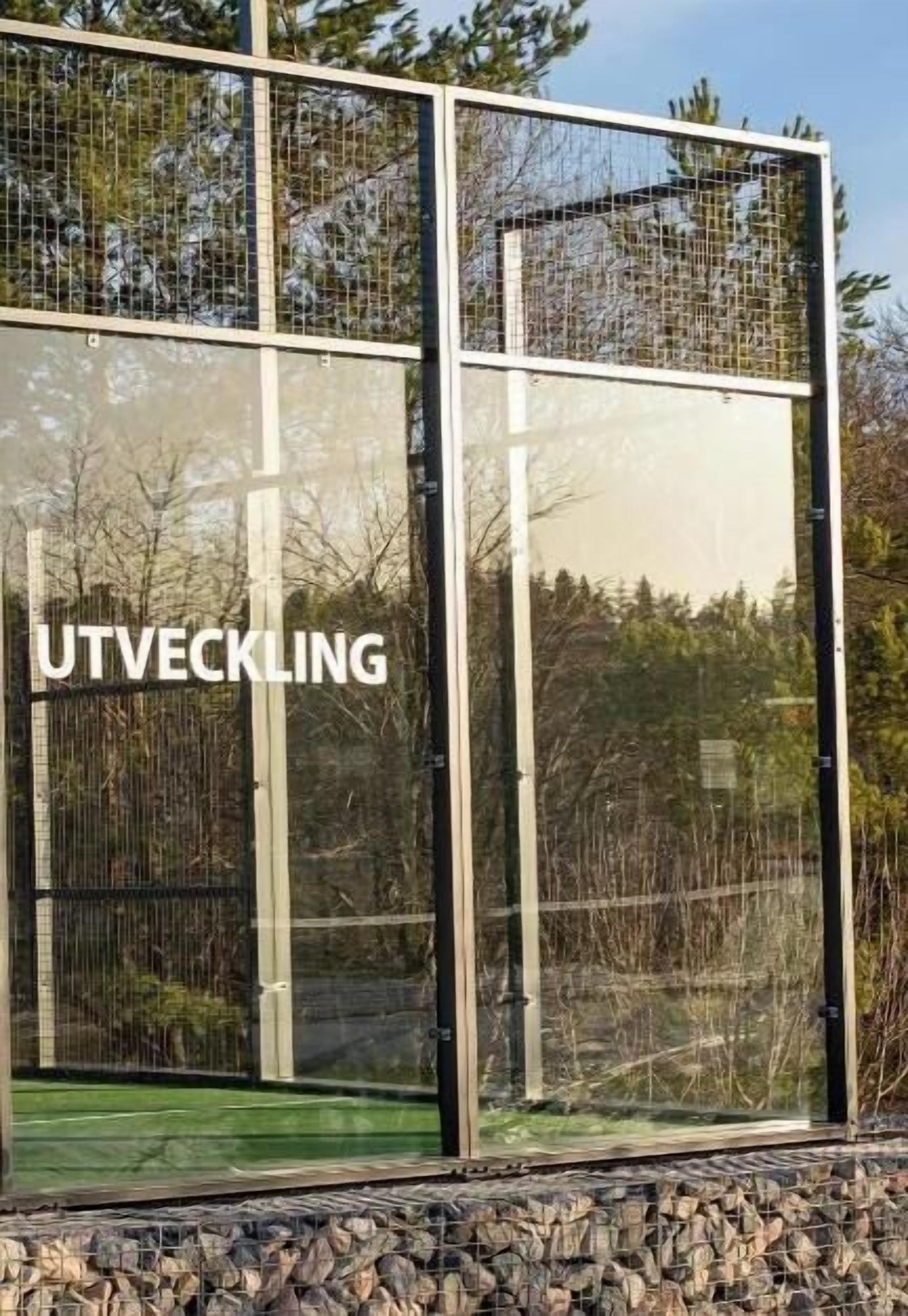 Un edificio moderno con estructura metálica y paneles de vidrio, con la leyenda 'UTVECKLING'.