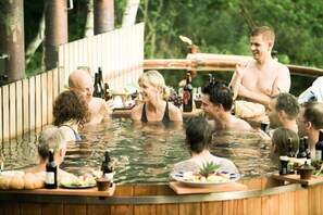 A group of people in a hot tub with bottles and plates of food. - Skeviks Gård (Värmdö)