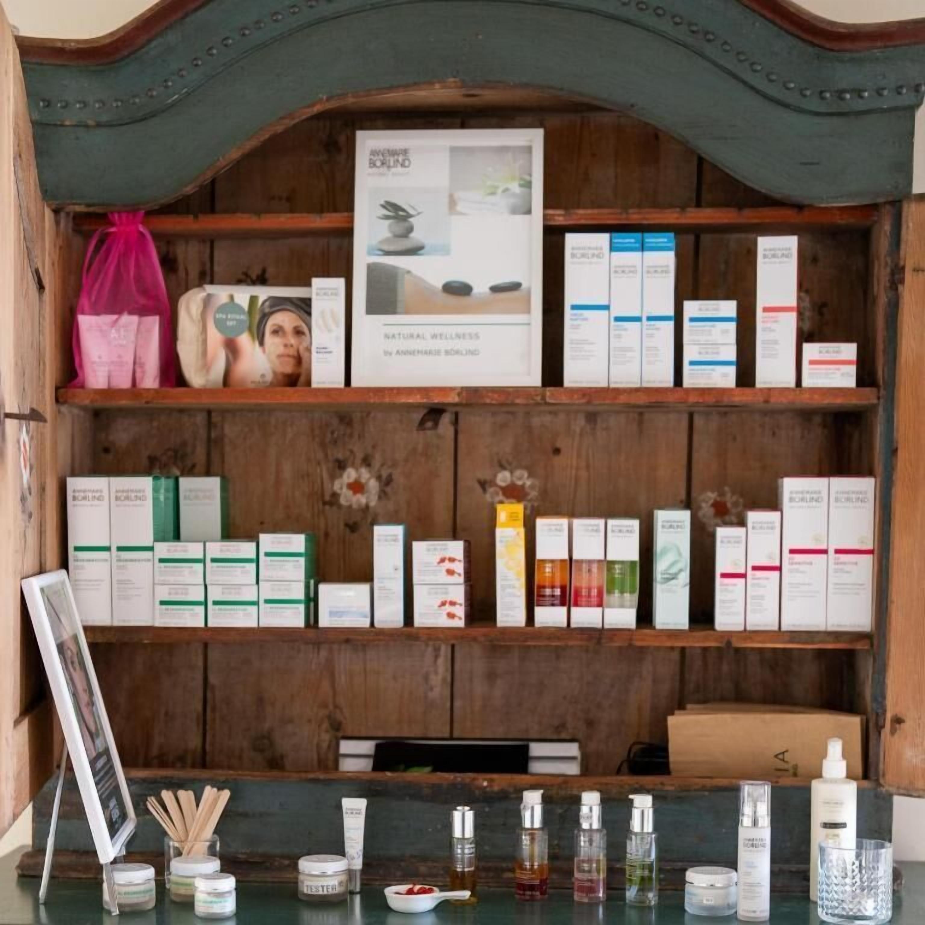 Estante de madeira com diversos produtos de cuidados para a pele e um quadro emoldurado.