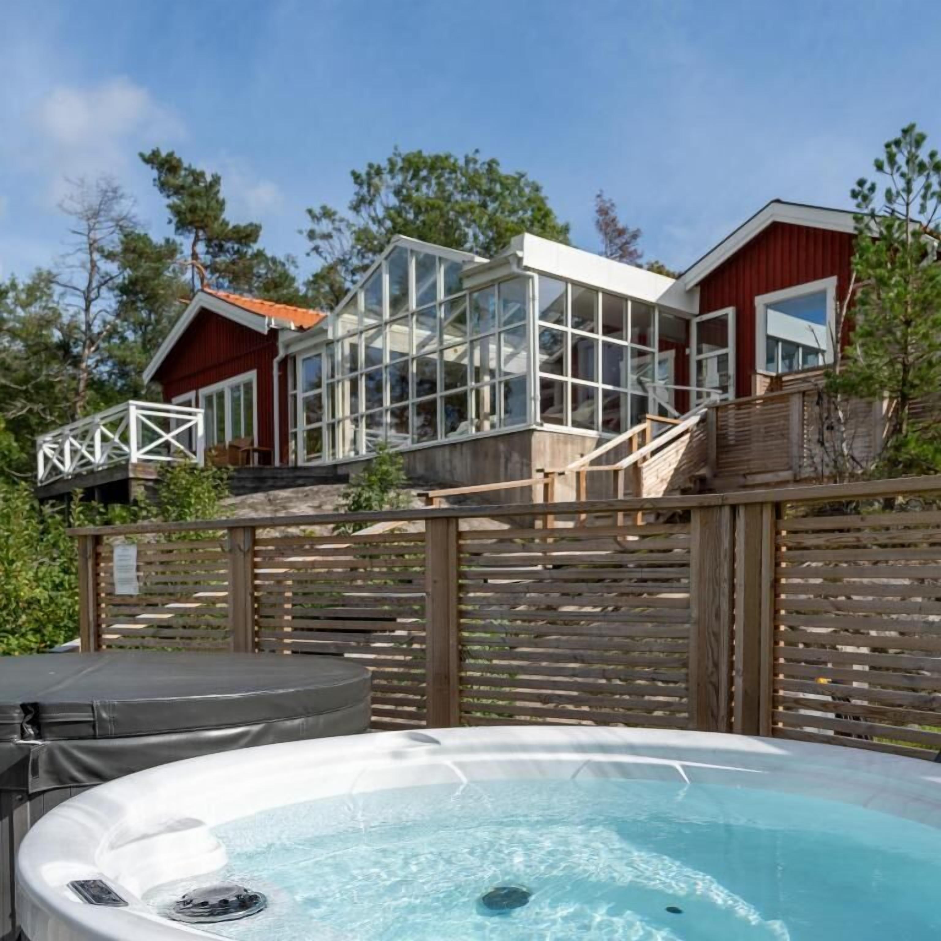 Une maison moderne dotée d’un jacuzzi et d’une terrasse en bois.