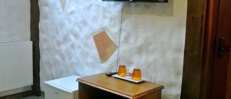 A small room with a white radiator, a wooden cabinet, and a television mounted on the wall.