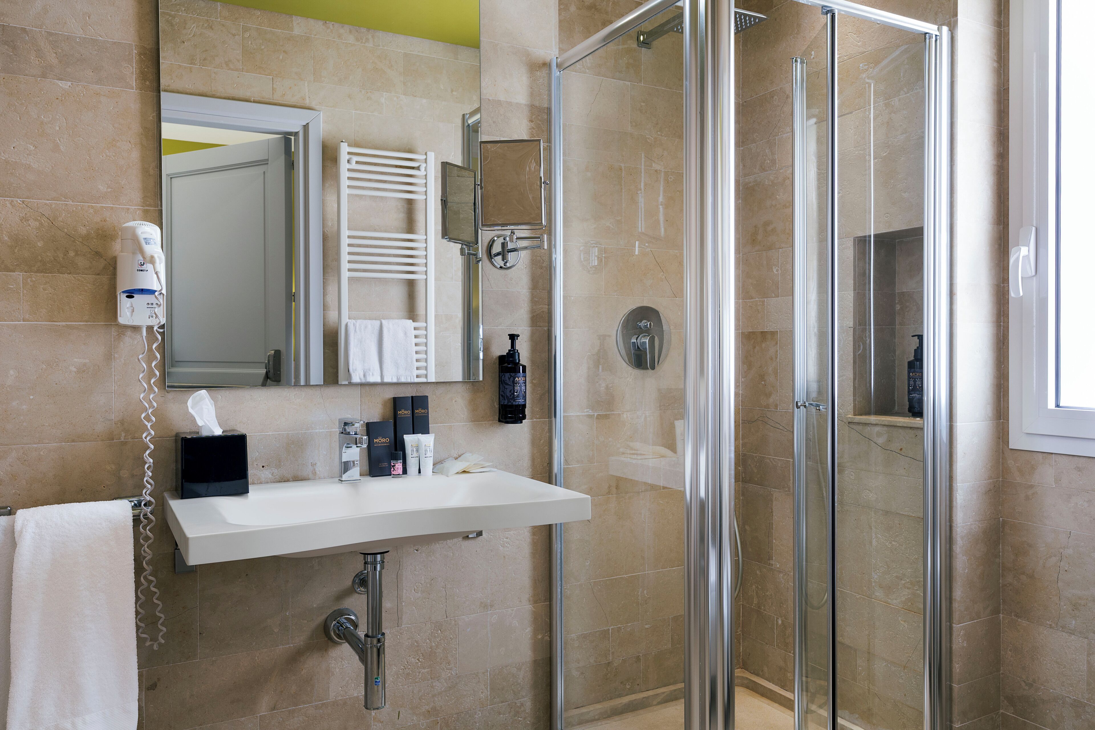 A bathroom with a glass shower enclosure, a white sink, and a mirror above it.