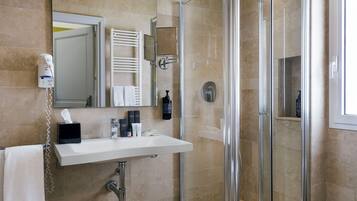 A bathroom with a glass shower enclosure, a white sink, and a mirror above it.