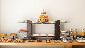 Un bufé de desayuno con diversas opciones de pastelería, frutas y bebidas.