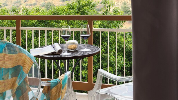 Un balcón con una mesa redonda, dos sillas y vistas a un paisaje montañoso.
