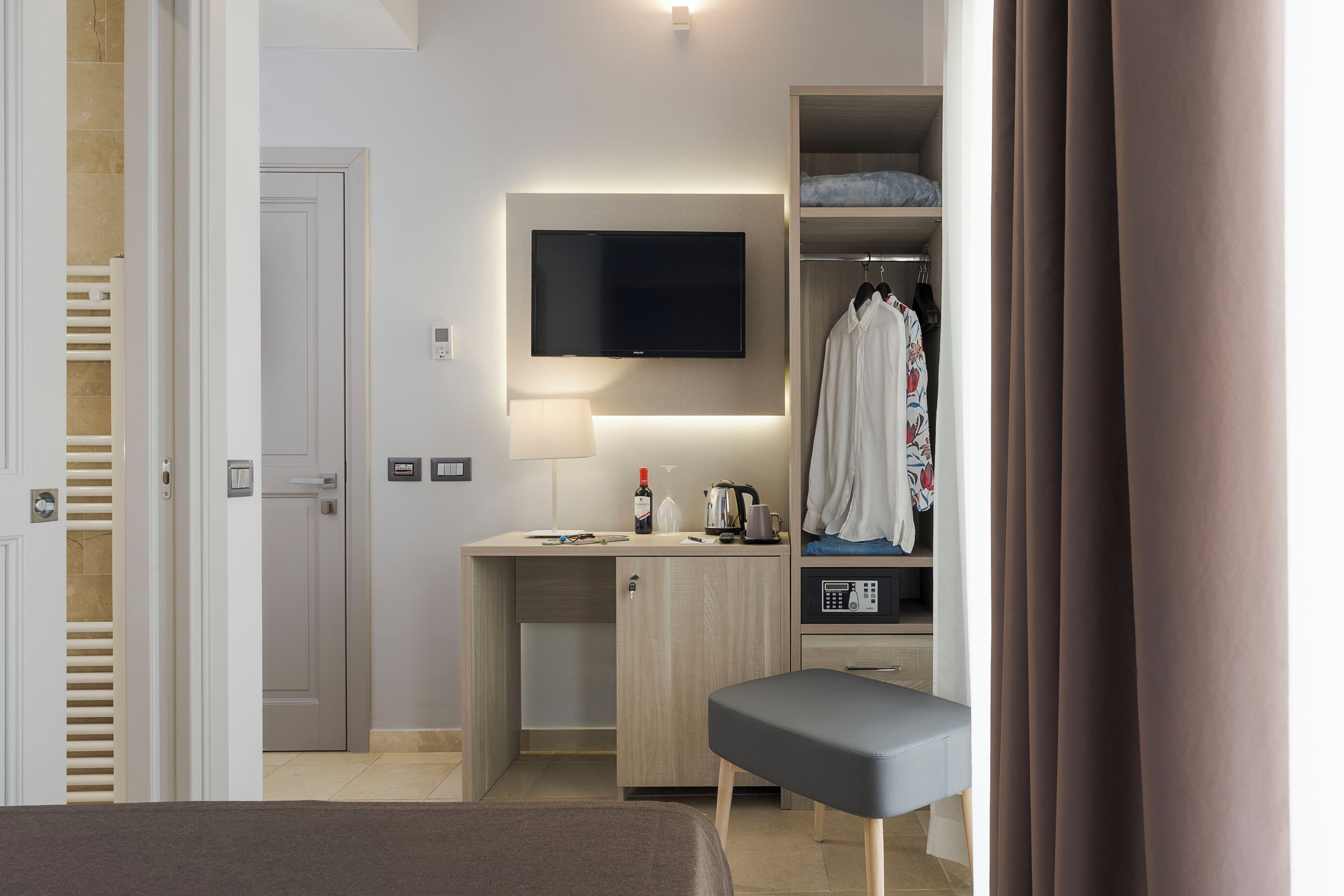 A hotel room with a bed, a desk with a TV, a wardrobe, and a bedside table.