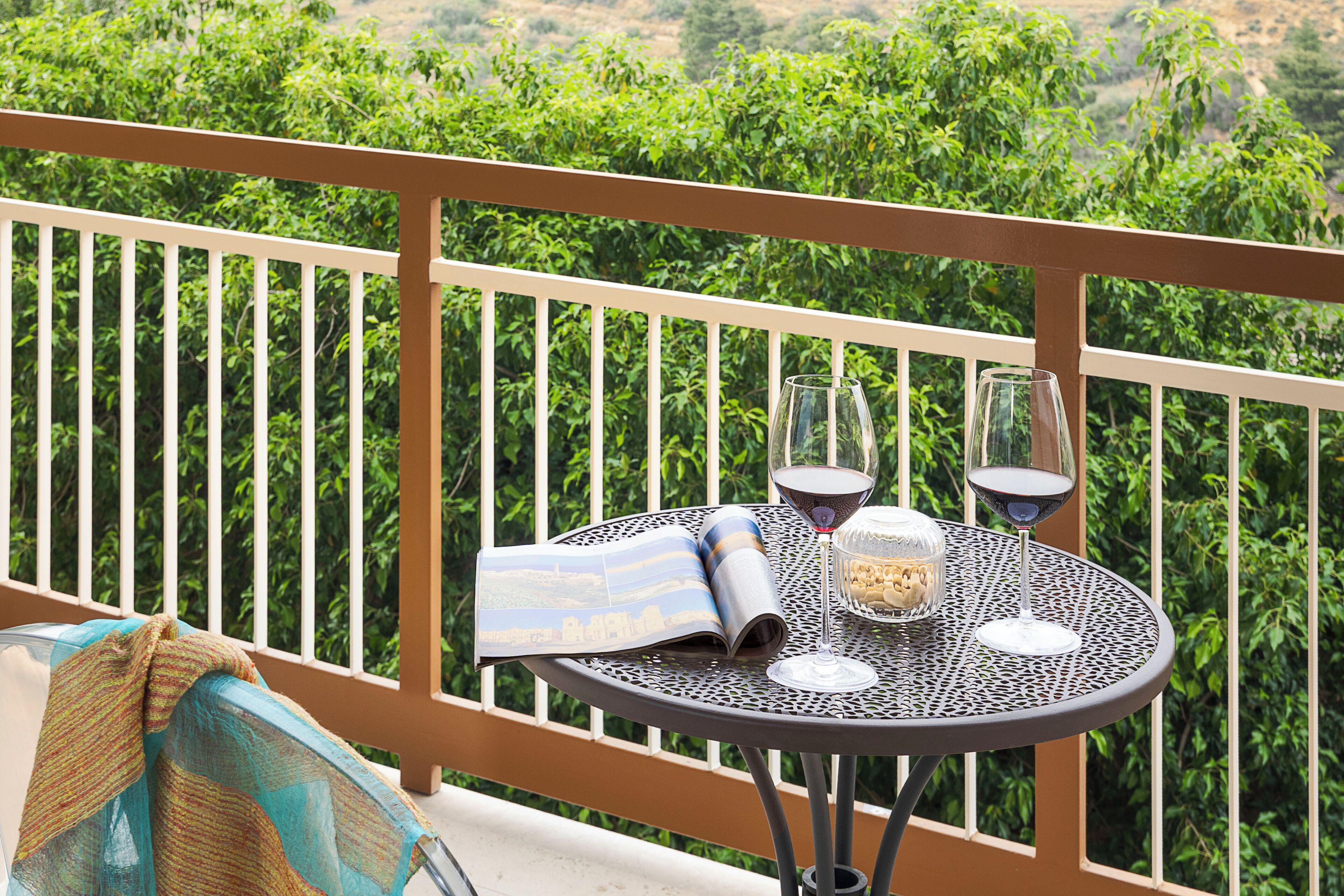Un balcon avec une table, deux verres à vin et un magazine.