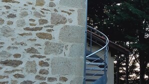 Ein Steinhaus mit einer Wendeltreppe, die zu einem Balkon führt.