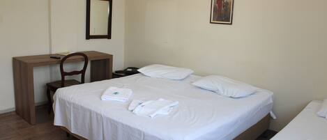 A hotel room with a single bed, a desk, and a chair.