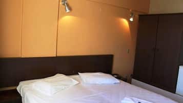 Una habitación de hotel con una cama, un armario y una lámpara de pared.