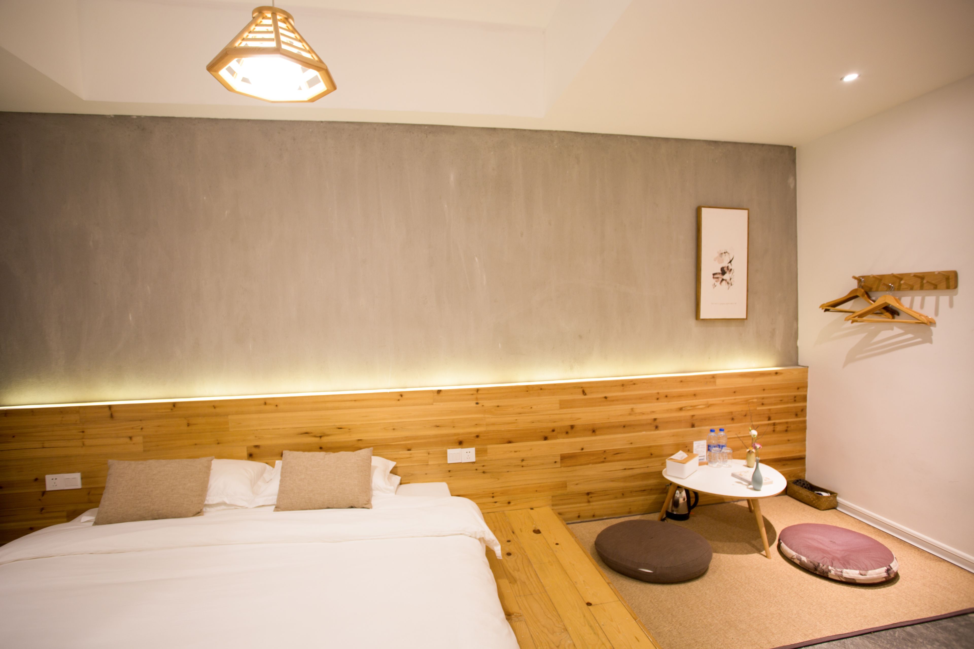 Una habitación de hotel moderna con cabecera de madera, una mesa redonda con un florero y un pequeño rincón de descanso.