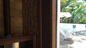 A stone wall with a wooden frame, a pool area with lounge chairs and umbrellas, and a stone floor. - Hotel La Ponsa Itatiaia (Itatiaia)