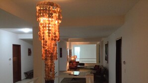 A hallway with a unique light fixture made of spherical objects, a glass table, and a seating area with a sofa and a chair. - Hotel La Ponsa Itatiaia (Itatiaia)