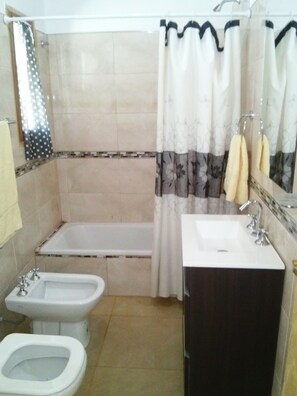 A bathroom with a bathtub, a sink, a bidet, and a mirror. - Casa en Cafayate (Cafayate)