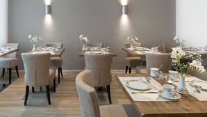 A dining area with multiple tables set for a meal, each with chairs and tableware.