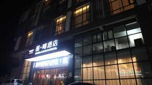 A hotel facade at night with illuminated signage and large windows. - James Joyce Coffetel Qifu Xincun Branch (Guangzhou)