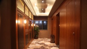 A hallway with wooden doors, a patterned carpet, and a potted plant. - James Joyce Coffetel Qifu Xincun Branch (Guangzhou)