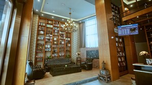 A spacious lobby with a large bookshelf, a leather sofa, and a chandelier. - James Joyce Coffetel Qifu Xincun Branch (Guangzhou)