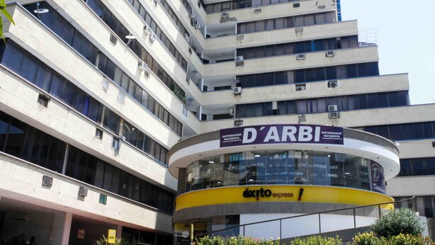 A multi-story building with a curved yellow and white structure labeled "D'ARBI" and "exito express".